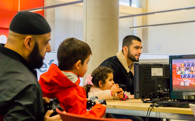 Two men help two young children with a computer activity