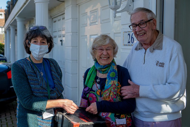 Two librarians smile as they deliver a package to a woman.