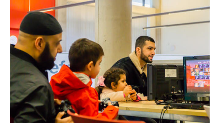 Two men help two young children with a computer activity