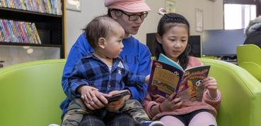 Woman reading with two children in a library