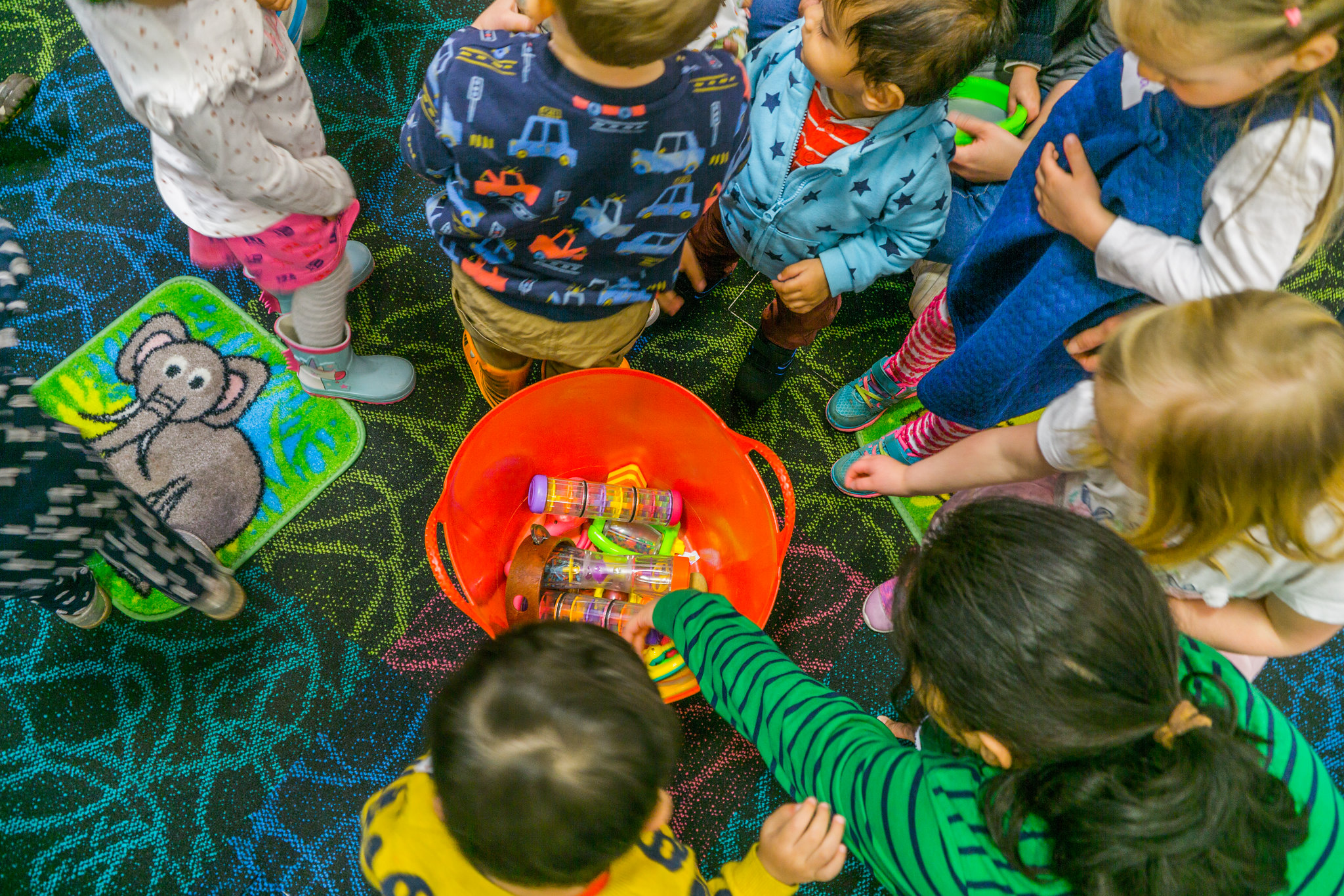 Young children in a library around a bucket