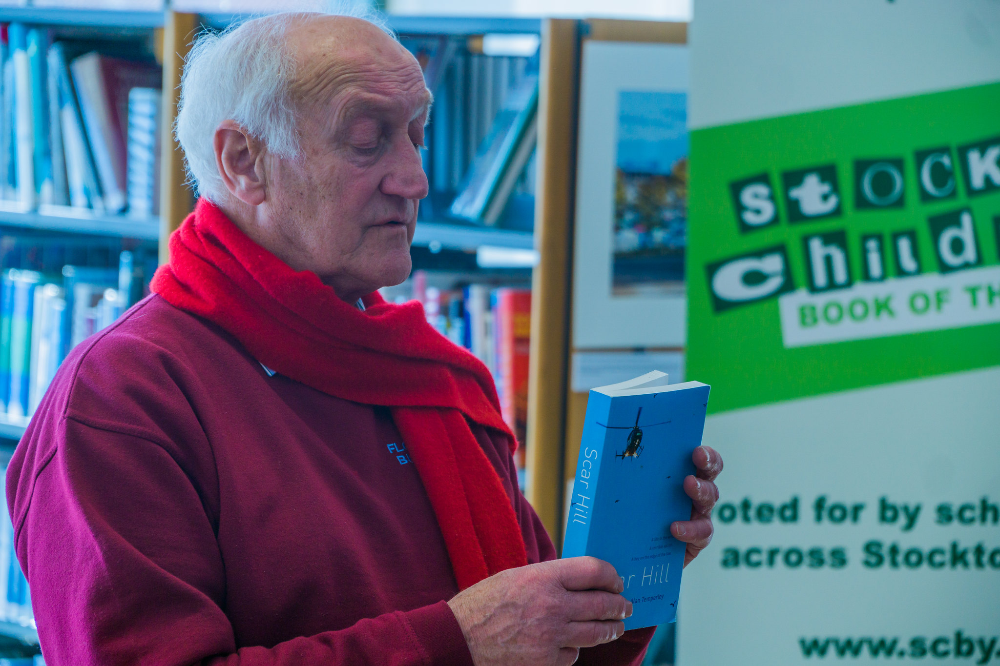 Older man reading a book in a library