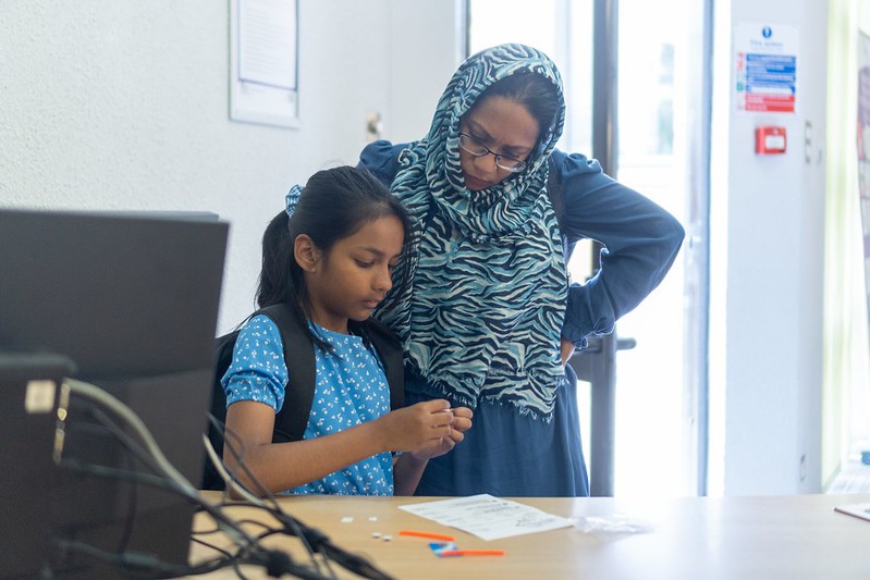 A woman observes a child performing a manual exercise in a library