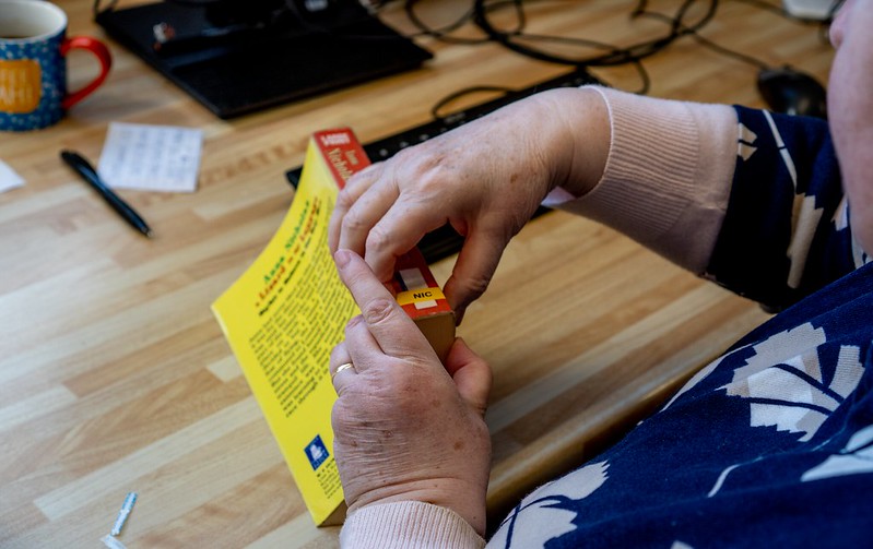 Two hands are seen manipulating the spine of a library book.