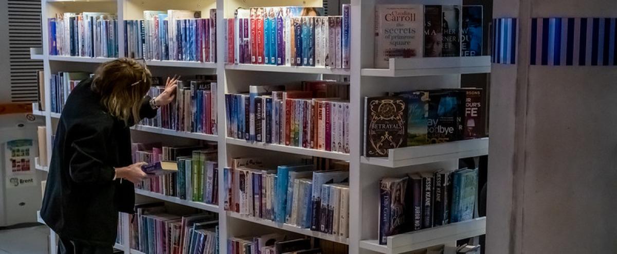 A female librarian checks stock on the shelves. A female librarian checks stock on the shelves.