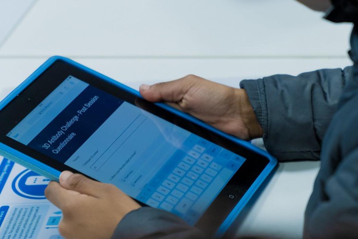 A child&#039;s hand is seen holding an iPad.