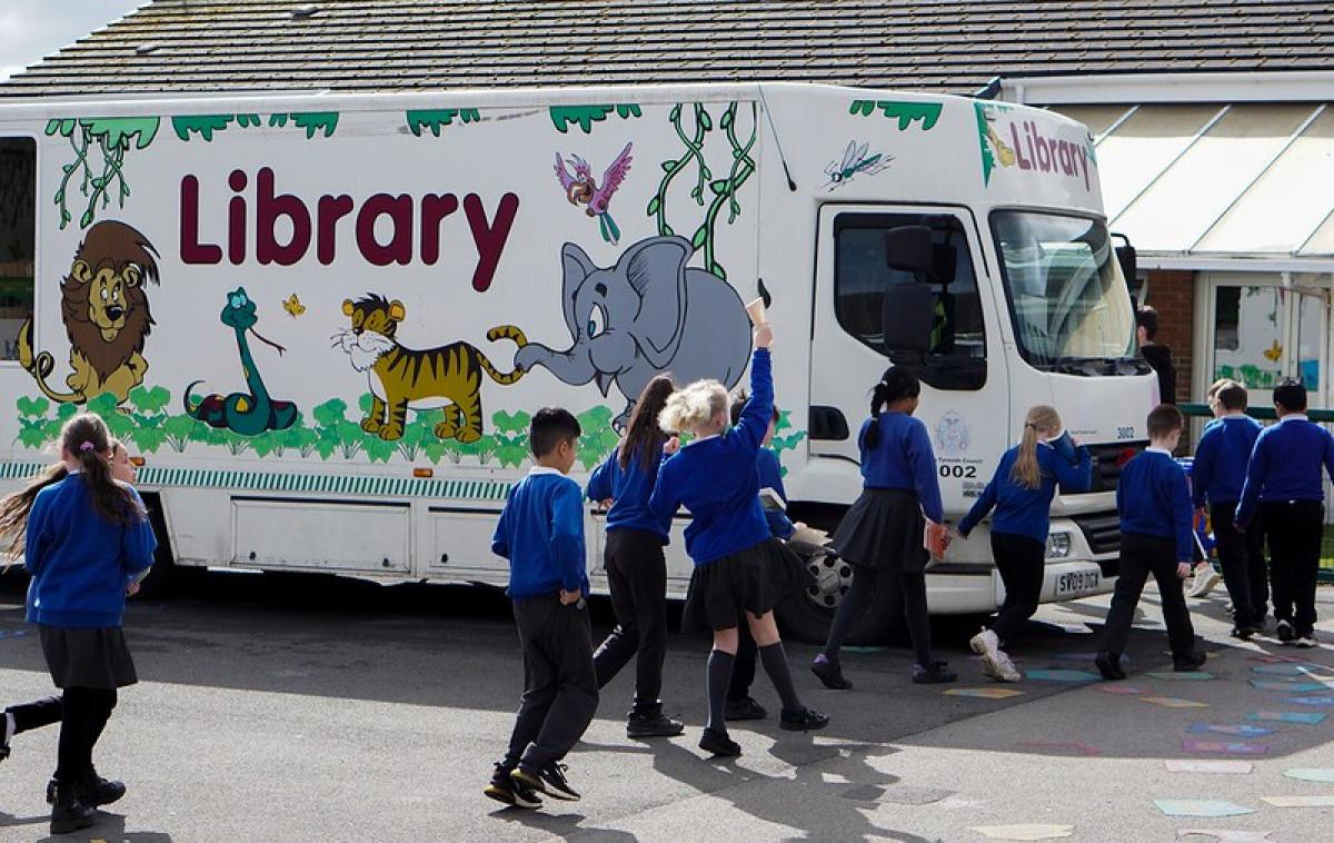 Schoolchildren jump in the air as they pass a monile library.