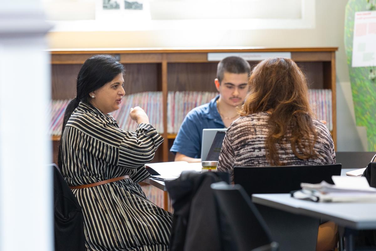 Two women discuss something at a library table.