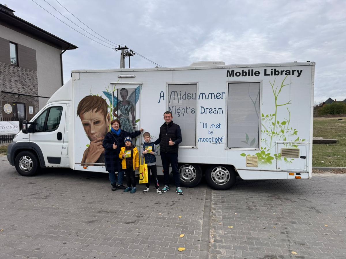 A family stands in front of a Ukrainian mobile library.