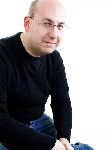 Ian Anstice BEM half smiles at the camera. He is wearing glasses and a dark sweatshirt.