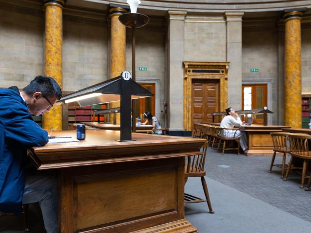 A man studies a document in a library.