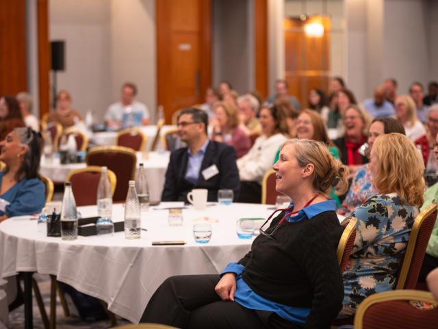 Photo of audience sat around tables