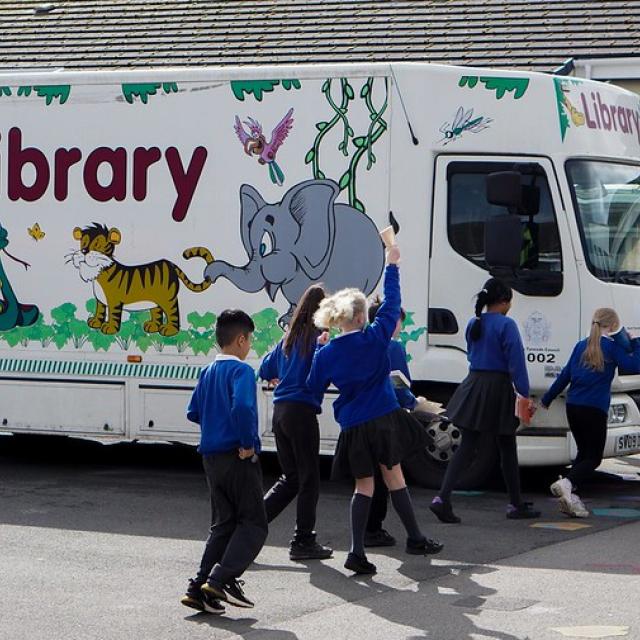 Schoolchildren jump in the air as they pass a monile library.