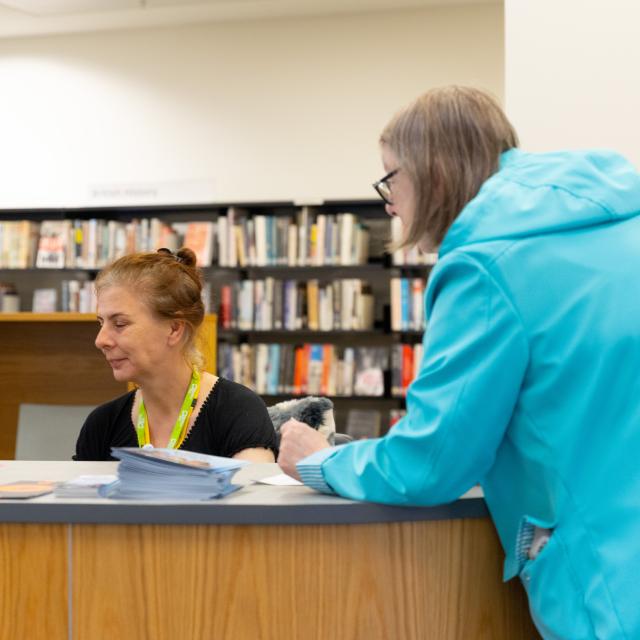 A female librarian advises a customer.