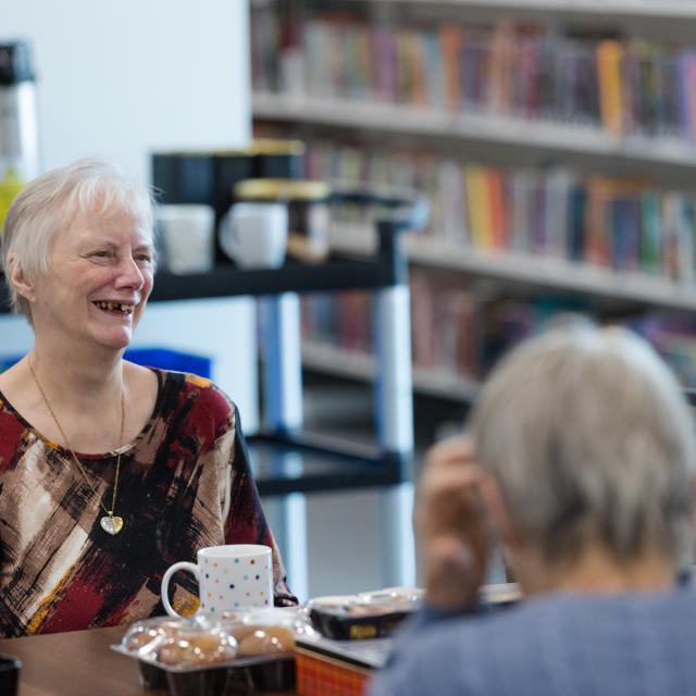 A woman smiles as she talks in a library.