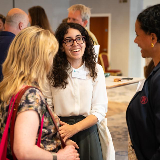 People chatting and smiling at a networking event.