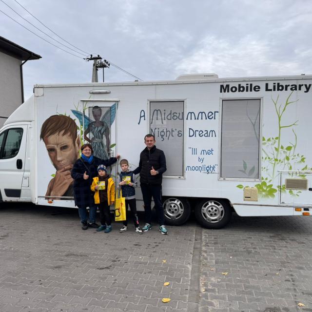 A family stands in front of a Ukrainian mobile library.