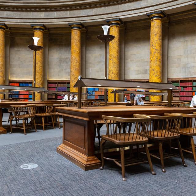 The inside of a public library showing wooden desks and chairs.
