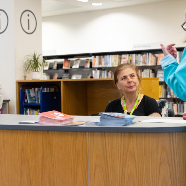 A female customer asks for advice at a library information desk.