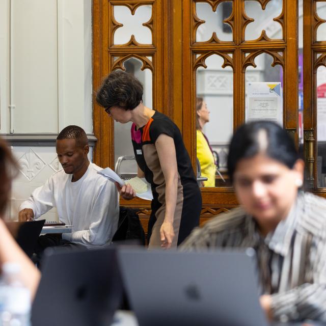 Two women are seen working at laptops in a library.