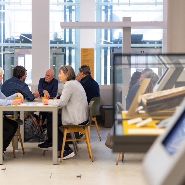 A group of people sit talking at a table in a library.