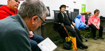 A group of older citizens sit and talk on chairs in a library.